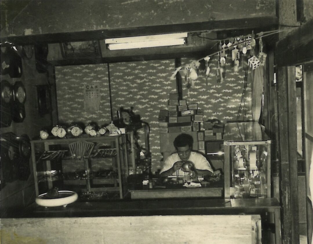 創業当時の店内で、時計と向き合いながら技を磨く若き日の故人の姿。